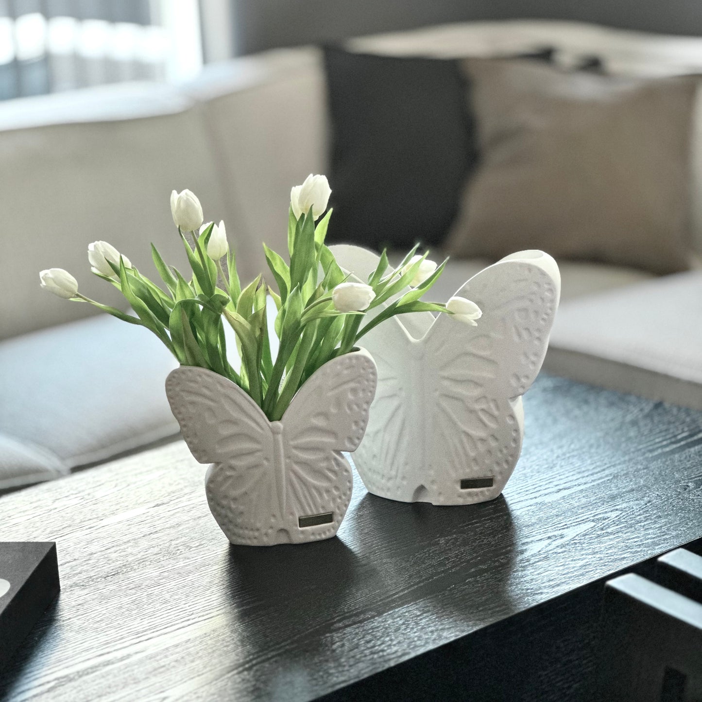 stor och liten vit vas på ett bord framför en soffa